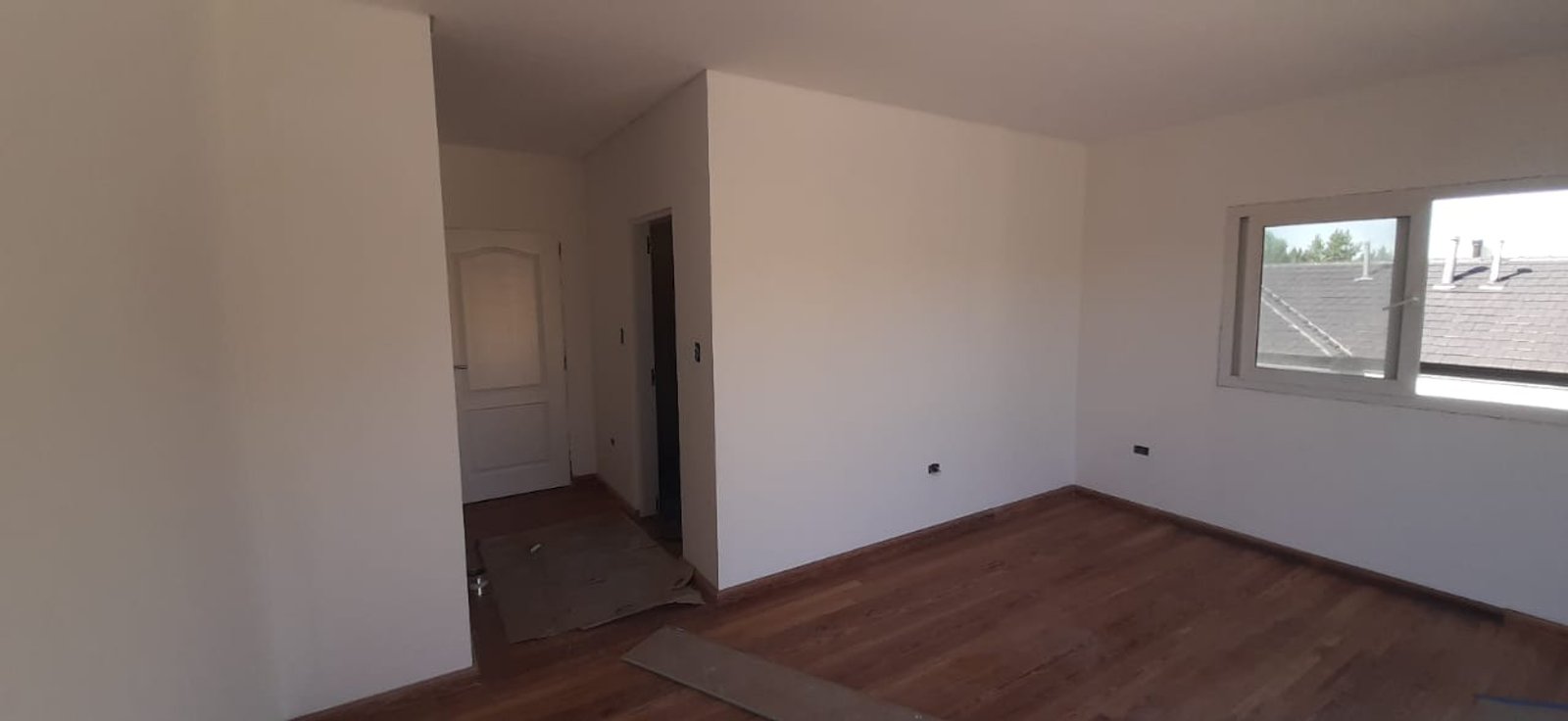 Interior vacío con piso de madera oscura y paredes blancas — proyecto Ampliación Residencial Barrio Terravista, por ODF Arquitectura & Obra, en Gral. Rodríguez